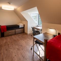 Double room with two beds, two desks and chairs, two sets of drawers, two armoires and a window.