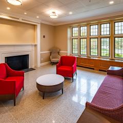 A lounge with a couch, two lounge chairs, a coffee table, a fireplace, and a large window.