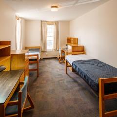 Double room with two beds, two desks and chairs, two dressers and a window.