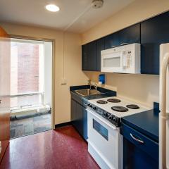 A small kitchen with a stove, countertops, sink, fridge, microwave, and cabinets.