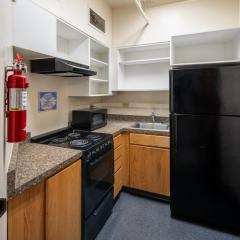 A small kitchen with cabinets and countertops, a sink, a fridge, a microwave, and a stove.