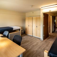 Double room with two beds, two desks and chairs, two armoires, and two sets of drawers.