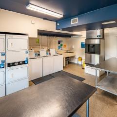 Laundry room with washers, dryers, and a table to fold laundry.