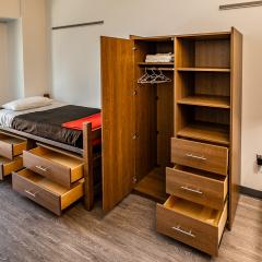 A bed with open drawers beneath it and an open armoire.