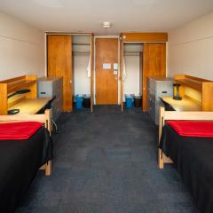 Double room with two beds, sets of drawers, desks and chairs, and two closets.