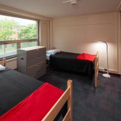 bedroom with two beds, drawers, closets and a window.