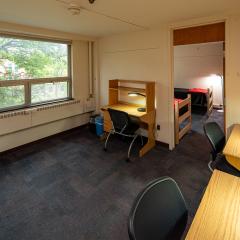 Shared room with four desks and chairs that connects to two double bedrooms