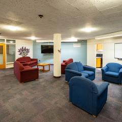 Lounge with four blue couches, three red couches, a coffee table and a tv.