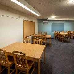 Room with four tables with four chairs at each table, a white board ad a cork board.