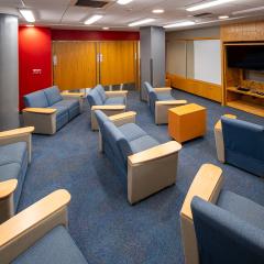 Room with 8 couches facing a tv and shelves