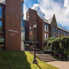brick and glass building with green shrubs and cloudy sky