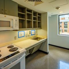 A small kitchen with cabinets and countertops, a sink, a fridge, a microwave, and a stove.