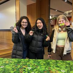 Three people behind a table with green St. Patrick's Day decor