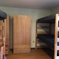 View of a room with three beds and two dressers.