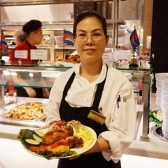 Kimeang standing in front of a serving line holding a plate of food
