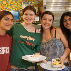 Four people smiling, two holding plates of food
