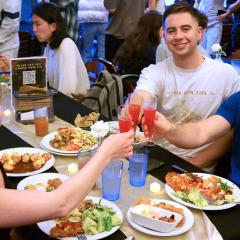 People at a dining table clink glasses