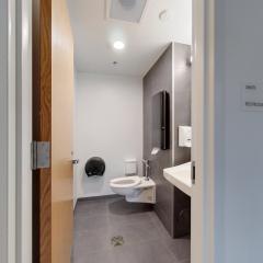 Photo showing the toilet, toilet paper dispenser, and sink in Ganędagǫ: Hall