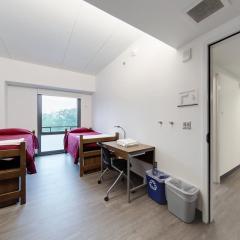 Double room with two beds, two desks and chairs, and a window.