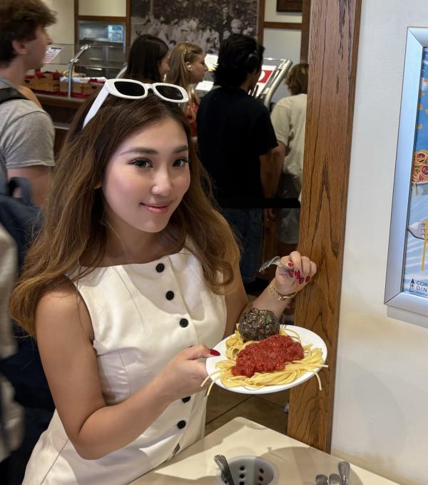 A person holds a plate of spaghetti and sauce
