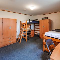 Double room with two beds, two desks and chairs, two armoires and a window.