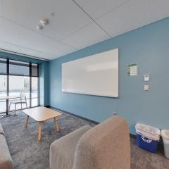 A floor lounge in Toni Morrison with a couch a lounge chair, a coffee table, and whipe board, and a large window.
